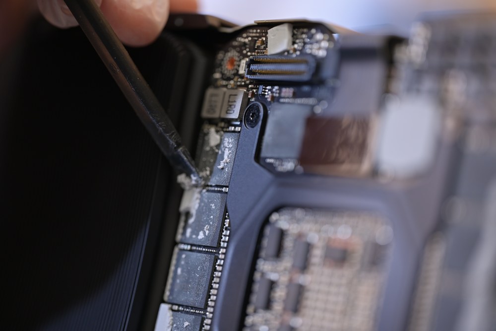A circuit board being worked on under magnification, probe in hand