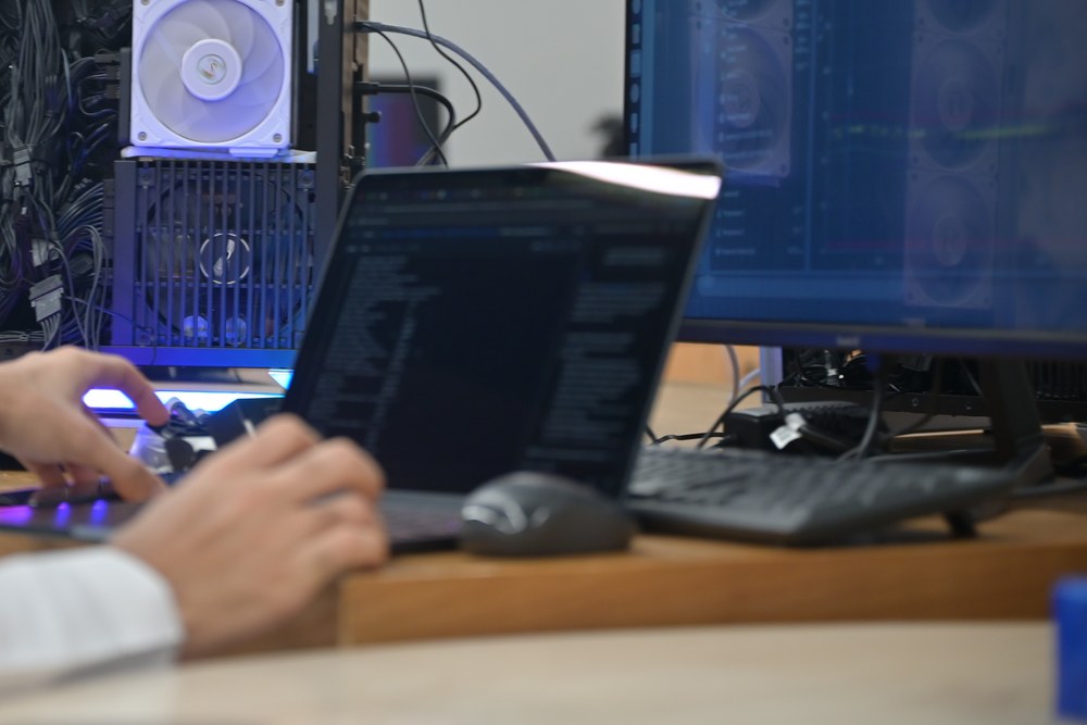 An engineer writing code beside an open node on the workshop bench