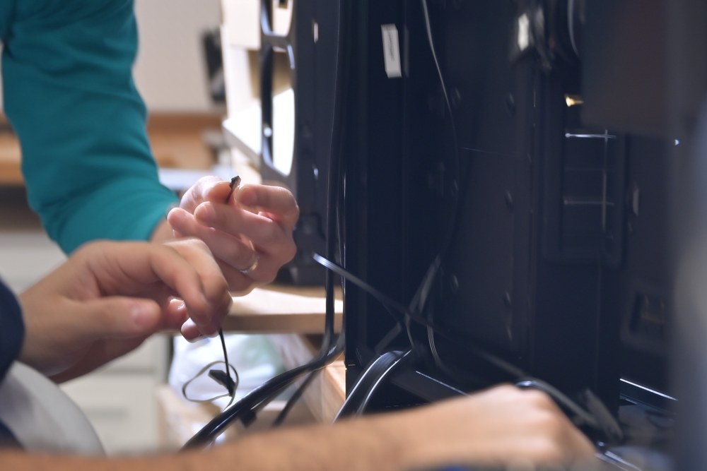 Two engineers routing cabling inside an open node on the bench